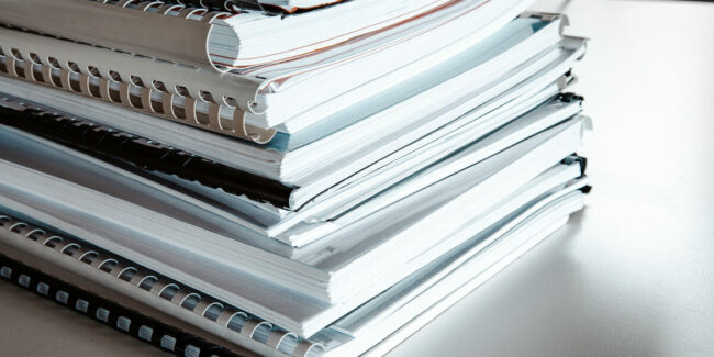 Stack of reports lies on a desk ready for review